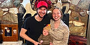 Bowen joined the competition — help win amazing prizes! antlers, baby, casual_clothing, cozy, cute, family, happy, hat, holding, home, indoor, infant, man, people, portrait, seated, smiling, stone_wall, woman, wooden_chest