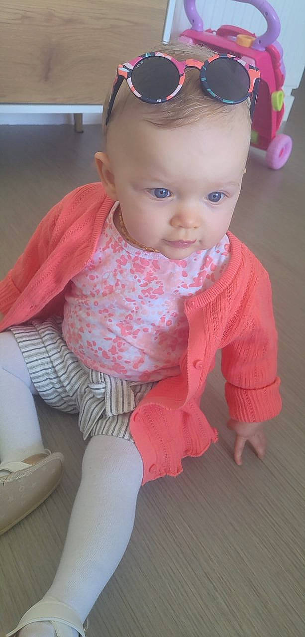 Liya a rejoint le concours — aidez-le/la à gagner de superbes lots ! baby, baby_toddler_clothing, blue, cheek, child, clothing, eyewear, face, facial_expression, flooring, goggles, hat, person, pink, skin, sleeve, standing, sunglasses, toddler, vision_care