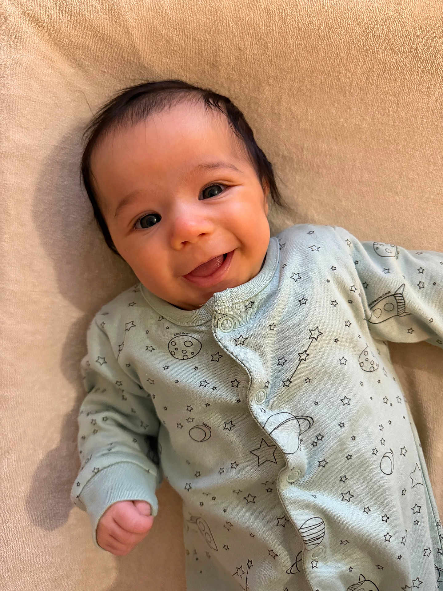 Youssef a rejoint le concours — aidez-le/la à gagner de superbes lots ! baby, infant, smile, onesie, space_theme, stars, planets, rocket, cute, lying_down, happy, face, child, soft_texture, beige_background, clothing, portrait, newborn, cozy, warm_lighting