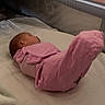 baby, infant, child, sleeping, pink_clothing, lying_down, raised_legs, mattress, crib, bedding, blanket, bedroom, indoor, portrait, face, profile, baby_suit, soft_lighting, home, photography