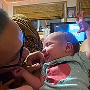 Elara joined the competition — help win amazing prizes! baby, infant, child, adult, face, glasses, smiling, cuddling, family, indoor, portrait, close_up, onesie, polka_dots, pink, blue, foot, living_room, television, led_lights