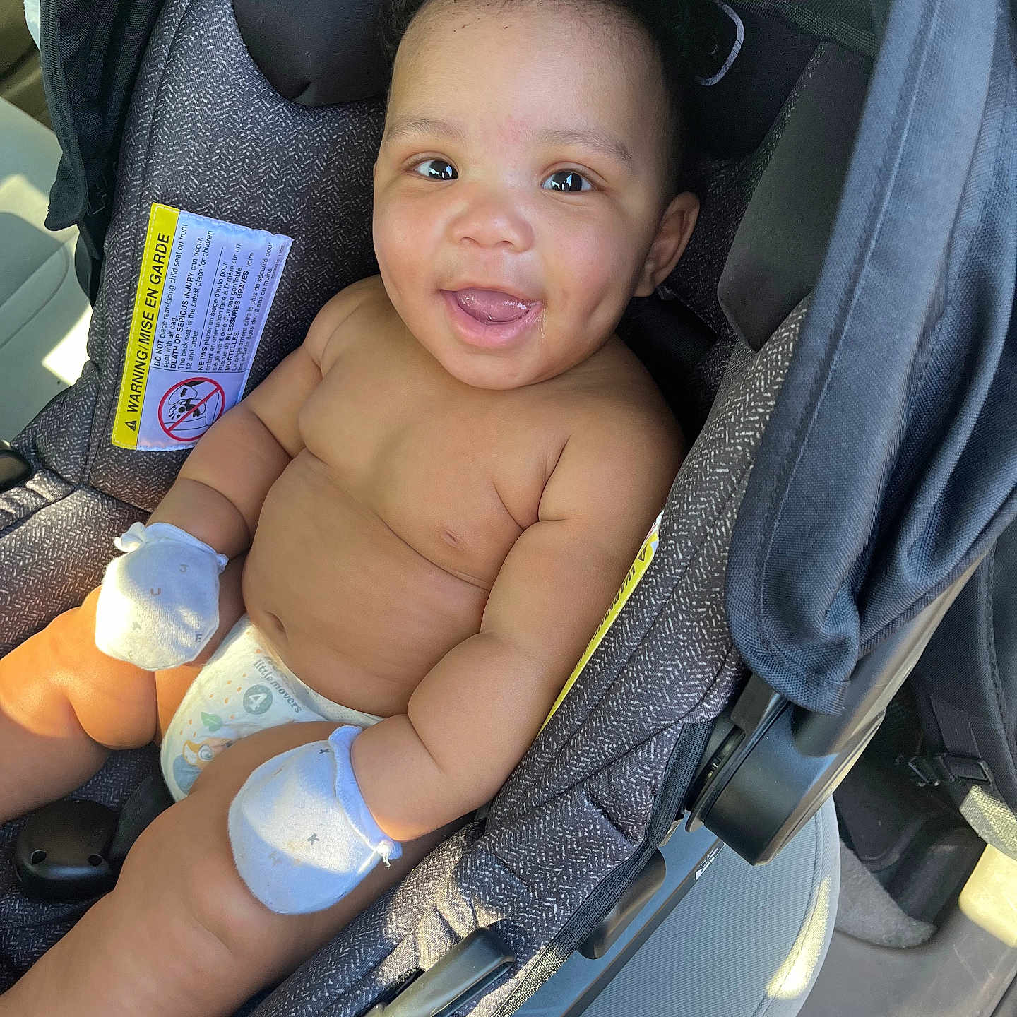 Kaynan is registered to the contest to win money with this photo: accessories, baby, car, car_interior, carseat, cushion, diaper, face, happy, head, homedecor, laughing, person, photography, portrait, smile, stroller, text, transportation, vehicle