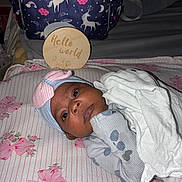 Princess joined the competition — help win amazing prizes! baby, infant, blanket, hat, bow, floral, striped, sheet, wooden_plaque, text, unicorn, bag, nursery, bed, pink, blue, white, face, person, cozy
