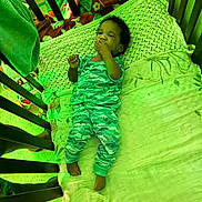 Giovanni is registered to the contest to win money with this photo: baby, crib, pajamas, blanket, toys, child, infant, sleepwear, cute, resting, hand, face, furniture, indoors, bed, smile, relaxing, colorful, person, cozy