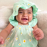 Keylanie is registered to the contest to win money with this photo: baby, child, smiling, happy, hat, dress, flower_pattern, daisy, green_clothing, cute, infant, portrait, closeup, indoors, soft_texture, skin, face, hand, sitting, joyful