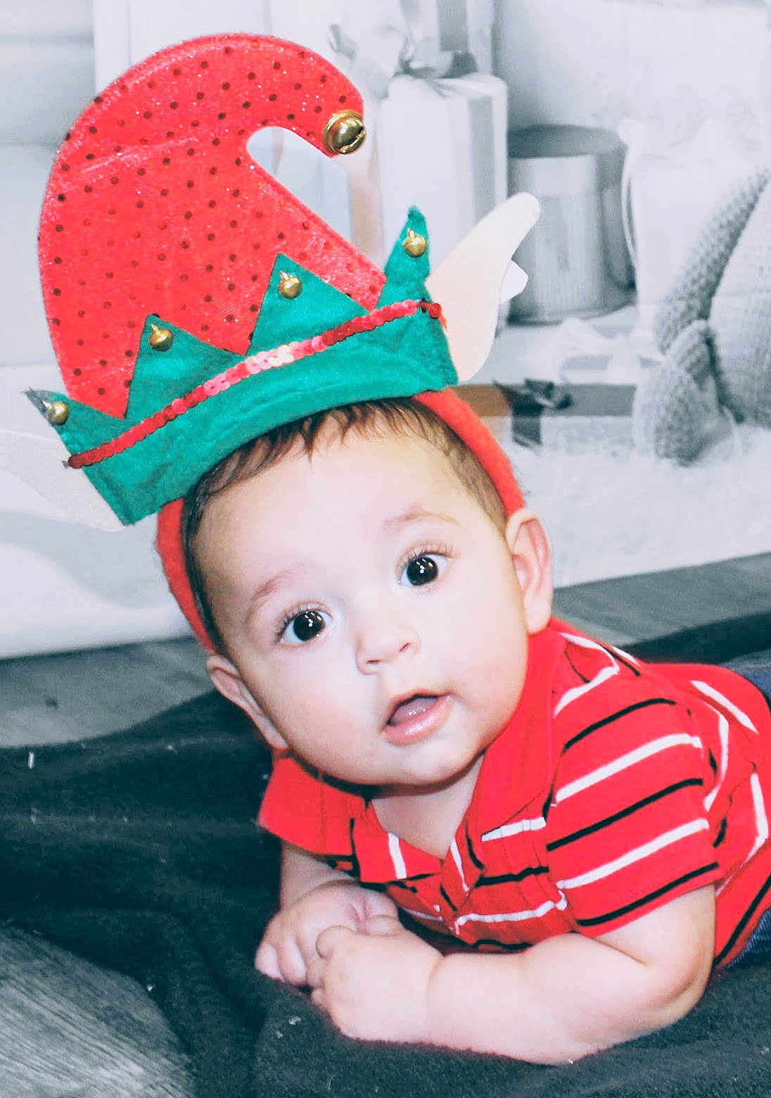 Ronen joined the competition — help win amazing prizes! baby, infant, child, face, eyes, hat, elf_hat, red_shirt, striped_shirt, hands, blanket, floor, indoors, cute, expression, holiday, festive, costume, person, portrait
