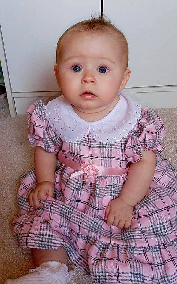 Amelia-rose is registered to the contest to win money with this photo: baby, baby_toddler_clothing, cheek, child, chin, dress, eye, eyelash, face, human_body, iris, lip, one_piece_garment, pattern, person, pink, plaid, skin, sleeve, surprise