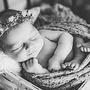 Delaney joined the competition — help win amazing prizes! baby, sleeping, flower_crown, blanket, basket, black_and_white, newborn, infant, soft_light, portrait, cozy, cute, peaceful, wrapped, headwear, closeup, indoors, resting, child, knit