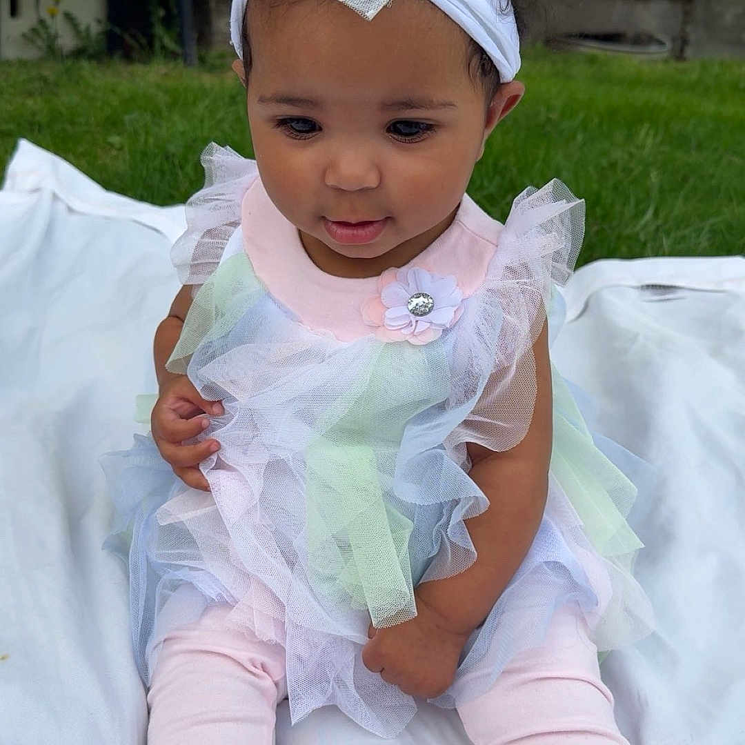 Lakyiah joined the competition — help win amazing prizes! baby, bunny, child, clothing, curly_hair, cute, flower_accessory, grass, headband, outdoor, pastel_colors, pink, portrait, ruffles, sitting, socks, soft_toys, toddler, white_blanket, young_child