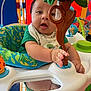 Sigberto is registered to the contest to win money with this photo: baby, child, infant, toy, activity_center, hand, face, green_clothing, colorful_background, playful, indoor, closeup, expression, curious, seat, mirror, plastic, playtime, young_child, early_childhood