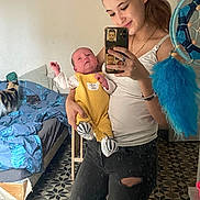 Aaron participe au concours pour gagner de l'argent avec cette photo : baby, woman, mirror, selfie, bedroom, cat, bed, dreamcatcher, yellow_outfit, knit_booties, tiled_floor, casual_clothing, smile, phone, reflection, home_interior, furniture, person, indoor, holding