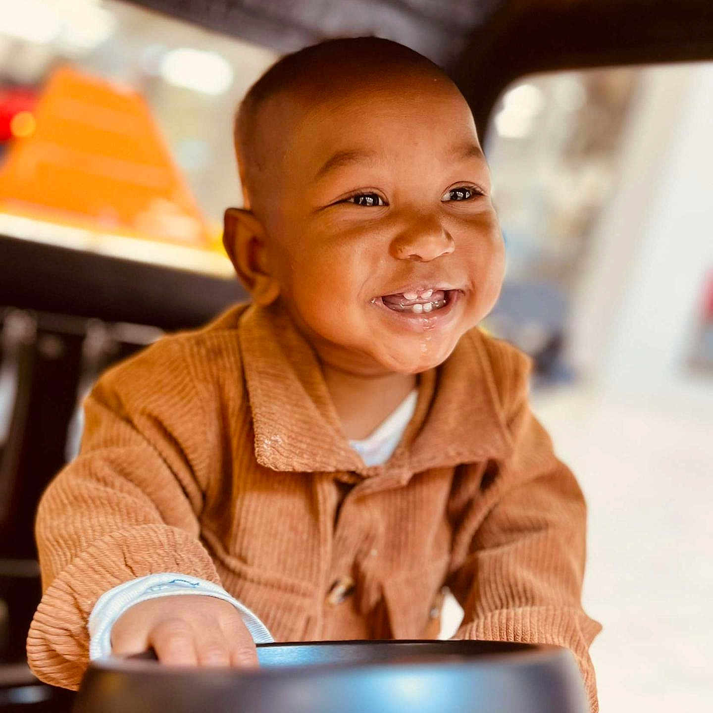 Da'Vonnie joined the competition — help win amazing prizes! baby, child, smiling, happy, portrait, sitting, vehicle, car_seat, tray, clothing, jacket, brown_clothing, infant, face, teeth, eyes, indoor, sunlight, close_up, joyful
