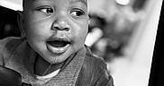 Da'Vonnie joined the competition — help win amazing prizes! baby, black_and_white, car_seat, child, close_up, clothing, curious, eyes, face, high_contrast, indoor, infant, monochrome, open_mouth, photography, portrait, sitting, sweater, travel, vehicle
