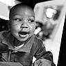 Da'Vonnie joined the competition — help win amazing prizes! baby, child, infant, car_seat, portrait, black_and_white, close_up, face, eyes, open_mouth, curious, sitting, travel, vehicle, clothing, sweater, indoor, photography, monochrome, high_contrast