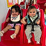 Serenity is registered to the contest to win money with this photo: baby, toddler, child, seat, red_seat, holding_hands, smiling, bib, clothing, indoor, play_area, harness, face, person, cute, happy, floor, footwear, shorts, pants