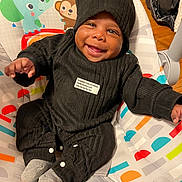 Syaire joined the competition — help win amazing prizes! baby, infant, smiling, black_clothing, hat, baby_seat, colorful_pattern, elephant_illustration, monkey_illustration, happy, indoor, cute, child, sock, seated, portrait, wooden_floor, toy, cozy, warm_lighting