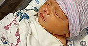 Tayshawn is registered to the contest to win money with this photo: newborn, baby, infant, sleeping, hospital, blanket, cap, footprints, bassinet, swaddled, wrapped, child, bed, medical, patient, cute, peaceful, person, indoors, resting