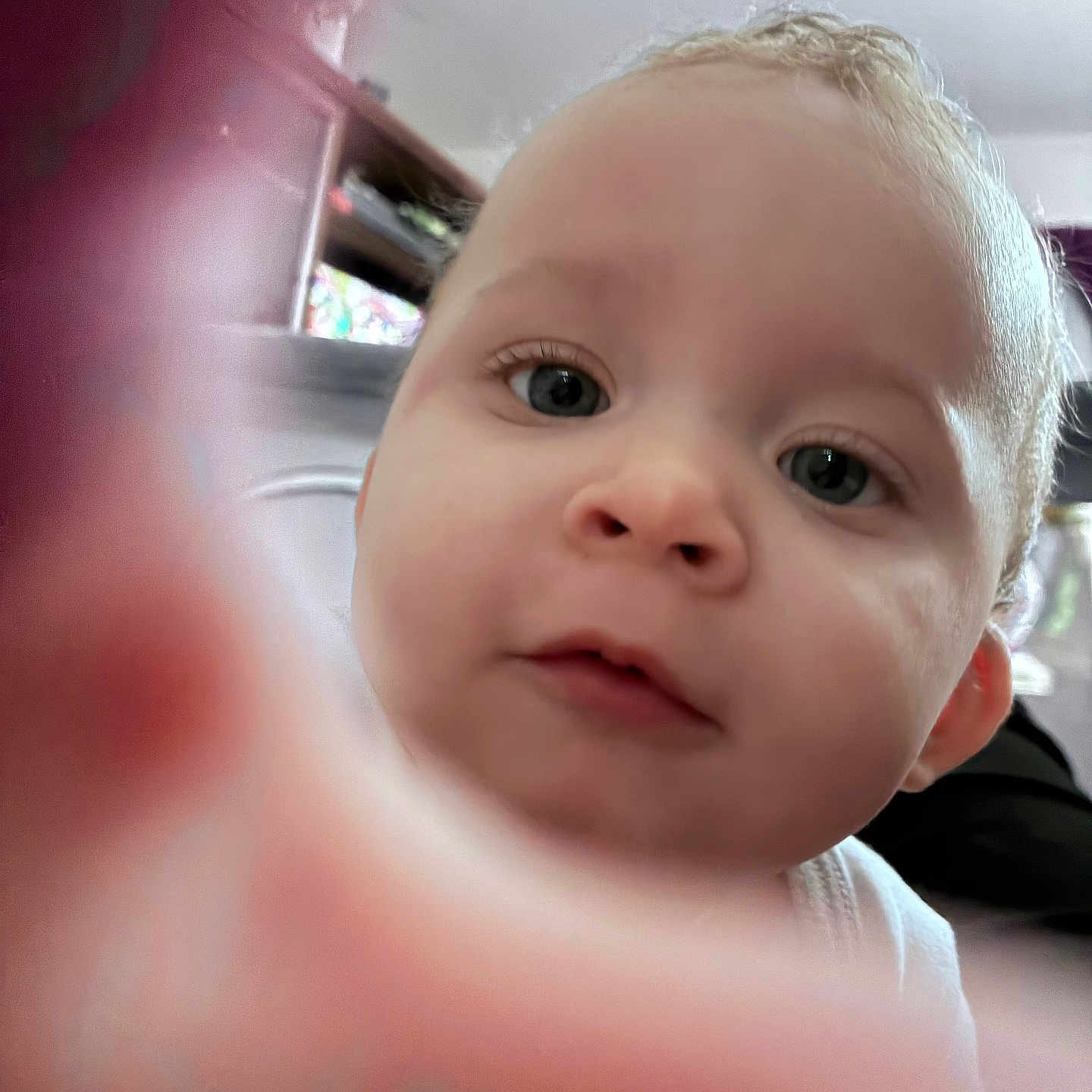 Zmarii is registered to the contest to win money with this photo: baby, ceiling, cheek, close_up, clothing, curious, cute, eyes, face, finger_blur, furniture, hand, indoor, infant, mouth, nose, photography, portrait, shelf, skin