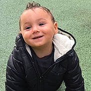 Eden participe au concours pour gagner de l'argent avec cette photo : toddler, child, smiling, black_jacket, crawling, playground, green_surface, grass, outdoor, happy, face, person, cute, young_child, jacket, play, fun, daylight, baby, park