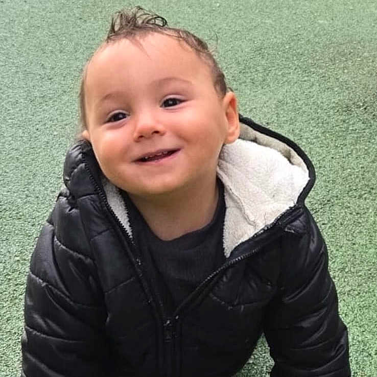 Eden participe au concours pour gagner de l'argent avec cette photo : baby, black_jacket, child, crawling, cute, daylight, face, fun, grass, green_surface, happy, jacket, outdoor, park, person, play, playground, smiling, toddler, young_child