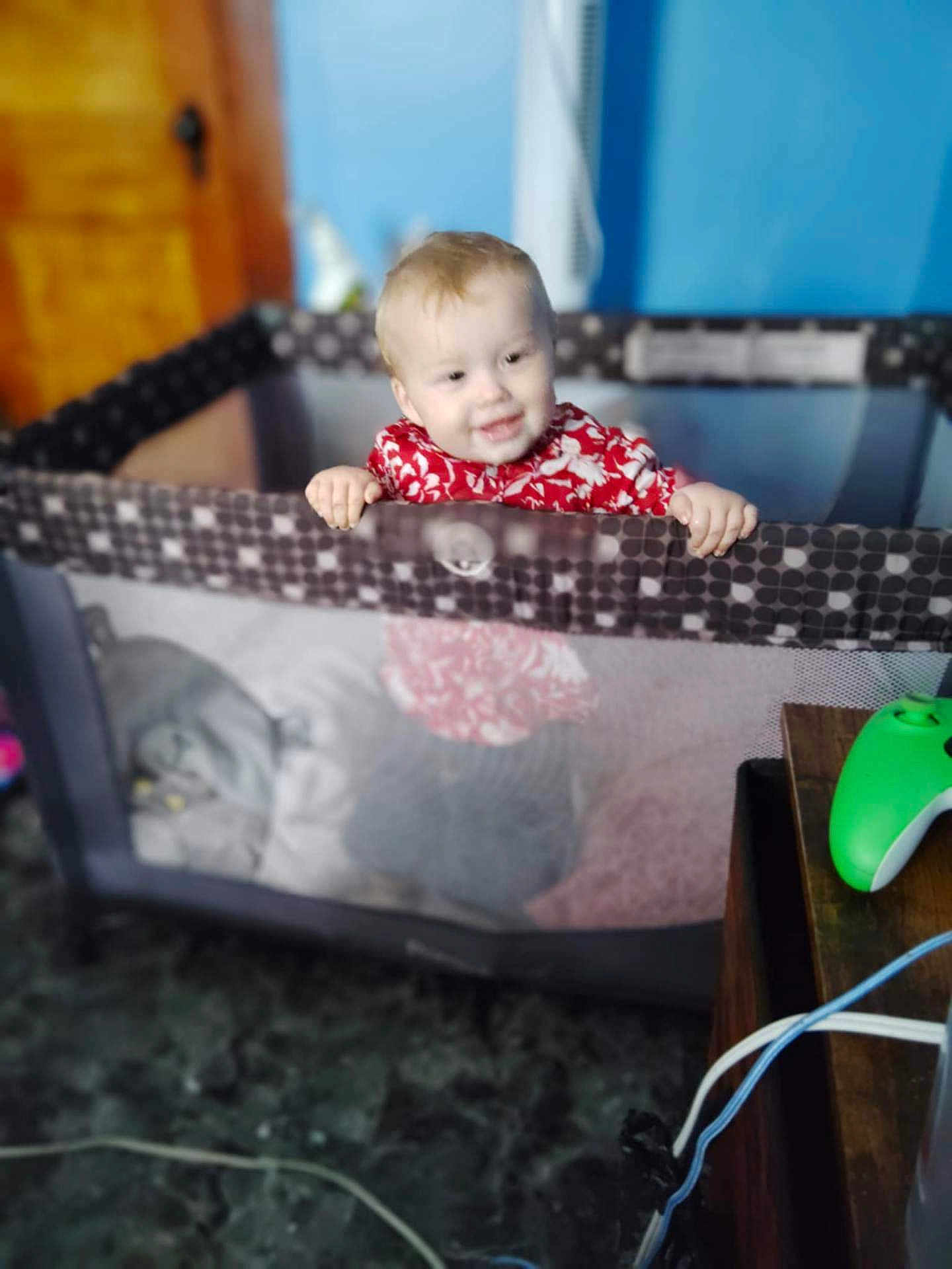 Robert joined the competition — help win amazing prizes! toddler, child, playpen, smile, indoor, red_clothing, wooden_door, blue_wall, gaming_controller, table, floor, baby, happy, person, furniture, hands, face, home, toy, room