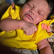 Kyla is registered to the contest to win money with this photo: baby, sleeping, yellow_clothing, infant, closeup, peaceful, soft_lighting, face, arm, skin, cute, portrait, indoors, child, newborn, hand, fingers, relaxation, comfort, babywear