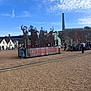 Ottilie is registered to the contest to win money with this photo: outdoor, art_installation, metal_sculpture, sky, clouds, people, child, historic_building, chimney, gravel, daytime, casual, crowd, sign, statue, raised_fist, peace_sign, blue_sky, public_space, exhibit