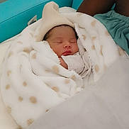 Lyria participe au concours pour gagner de l'argent avec cette photo : baby, newborn, infant, blanket, polka_dot_blanket, hat, sleeping, swaddle, cozy, bed, teal_background, adult_arm, sheet, closeup, peaceful, portrait, tiny_face, nursery, soft_texture, resting