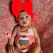 Oaklynn is registered to the contest to win money with this photo: baby, infant, red_bow, headband, chevrolet_logo, colorful_outfit, patchwork, pacifier, blanket, patterned_blanket, sitting, wide_eyes, cute, child, indoors, portrait, skin, hand, foot, expression