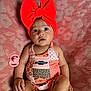 baby, infant, red_bow, headband, chevrolet_logo, colorful_outfit, patchwork, pacifier, blanket, patterned_blanket, sitting, wide_eyes, cute, child, indoors, portrait, skin, hand, foot, expression