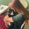 Oreo joined the competition — help win amazing prizes! person, cat, black_and_white_cat, hugging, cuddling, long_hair, brown_hair, green_shirt, plaid_pants, chair, indoor, home, bedroom, desk, book, carpet, sunlight, portrait, pet, cozy