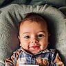 baby, infant, smile, face, eyes, plaid_shirt, clothing, blanket, soft_texture, cute, child, portrait, happy, young, indoors, laying_down, closeup, head, cheeks, skin