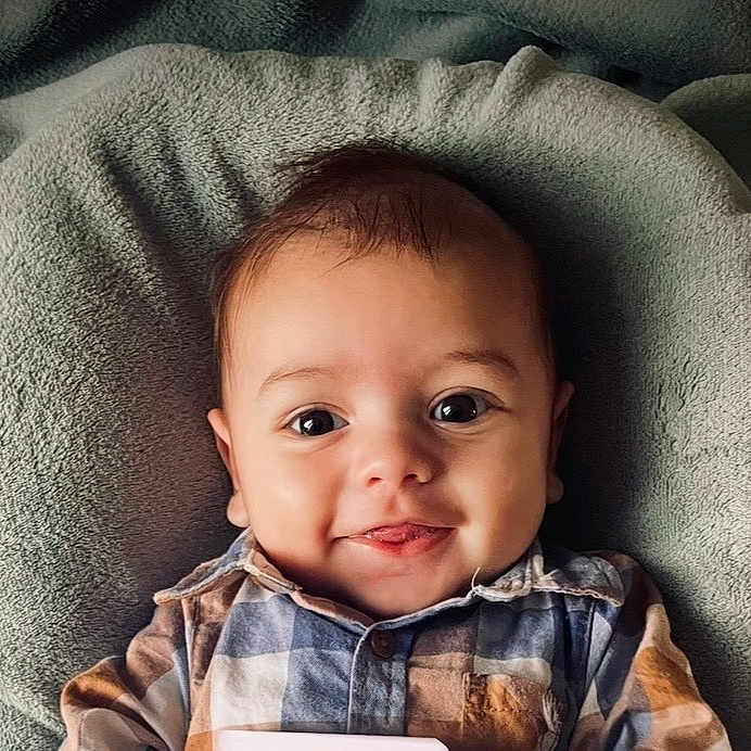 Evan a rejoint le concours — aidez-le/la à gagner de superbes lots ! baby, infant, smile, face, eyes, plaid_shirt, clothing, blanket, soft_texture, cute, child, portrait, happy, young, indoors, laying_down, closeup, head, cheeks, skin