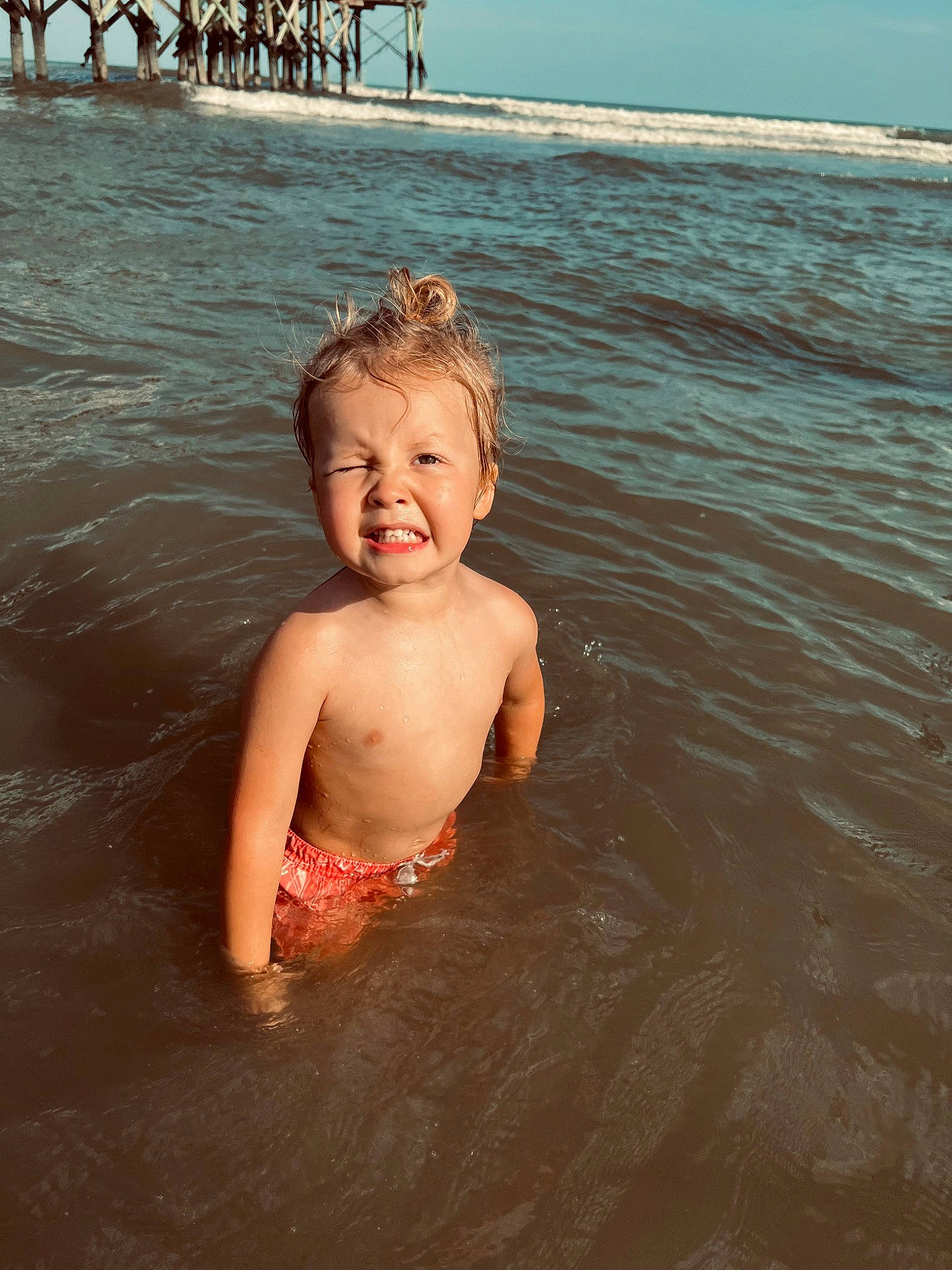 Aiden is registered to the contest to win money with this photo: barechested, bathing, beach, body_of_water, chest, child, eye, face, fun, happy, head, human_body, lake, leisure, people_on_beach, person, sky, smile, summer, toddler