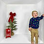 toddler, child, smiling, christmas_sweater, holiday, small_tree, red_bow, mailbox, letters_to_santa, barefoot, white_background, festive, joyful, indoor, cute, young_child, pants, standing, happy, pose