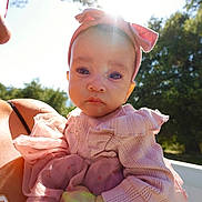 Aria is registered to the contest to win money with this photo: baby, child, pink_clothing, headband, outdoor, sunlight, trees, sky, person, portrait, cute, infant, hand, dress, nature, daylight, face, expression, holding, sunflare
