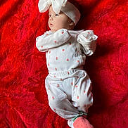 Kailani is registered to the contest to win money with this photo: baby, infant, white_clothing, headband, bow, red_blanket, strawberry_pattern, sock, lying_down, child, cute, soft_texture, fabric, portrait, small_person, newborn, indoors, peaceful, baby_girl, cozy