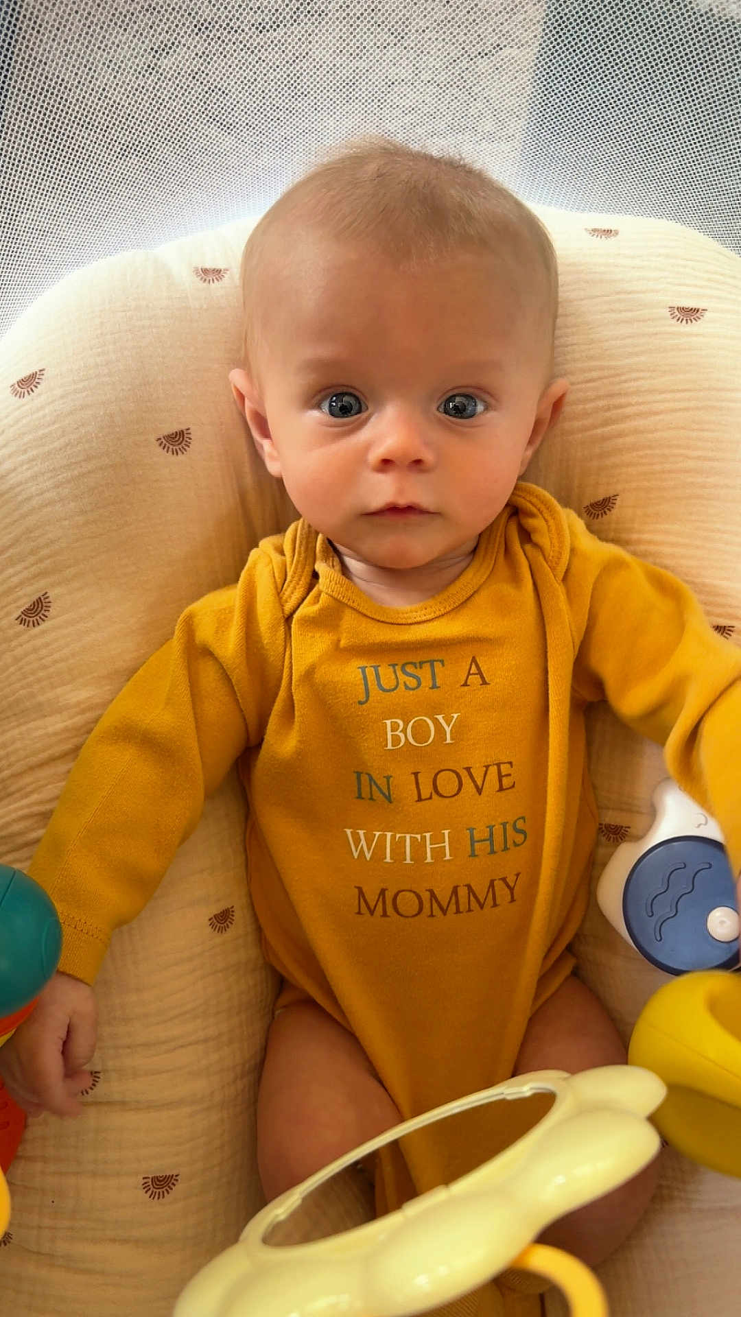 Max joined the competition — help win amazing prizes! baby, boy, infant, onesie, yellow_clothing, toy, cushion, seat, face, eyes, hand, cute, child, indoor, portrait, expression, curious, sitting, comfort, soft