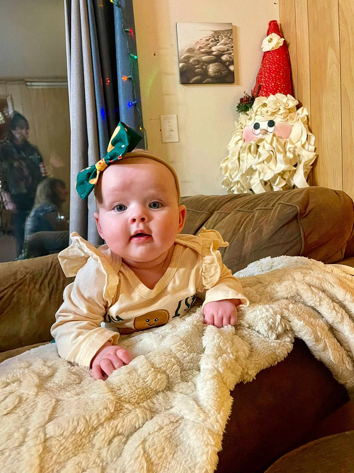 Leia is registered to the contest to win money with this photo: baby, child, bow, blanket, couch, curtains, decoration, face, festive, furniture, holiday, indoor, people, portrait, reflection, santa, smiling, toy, window, woman