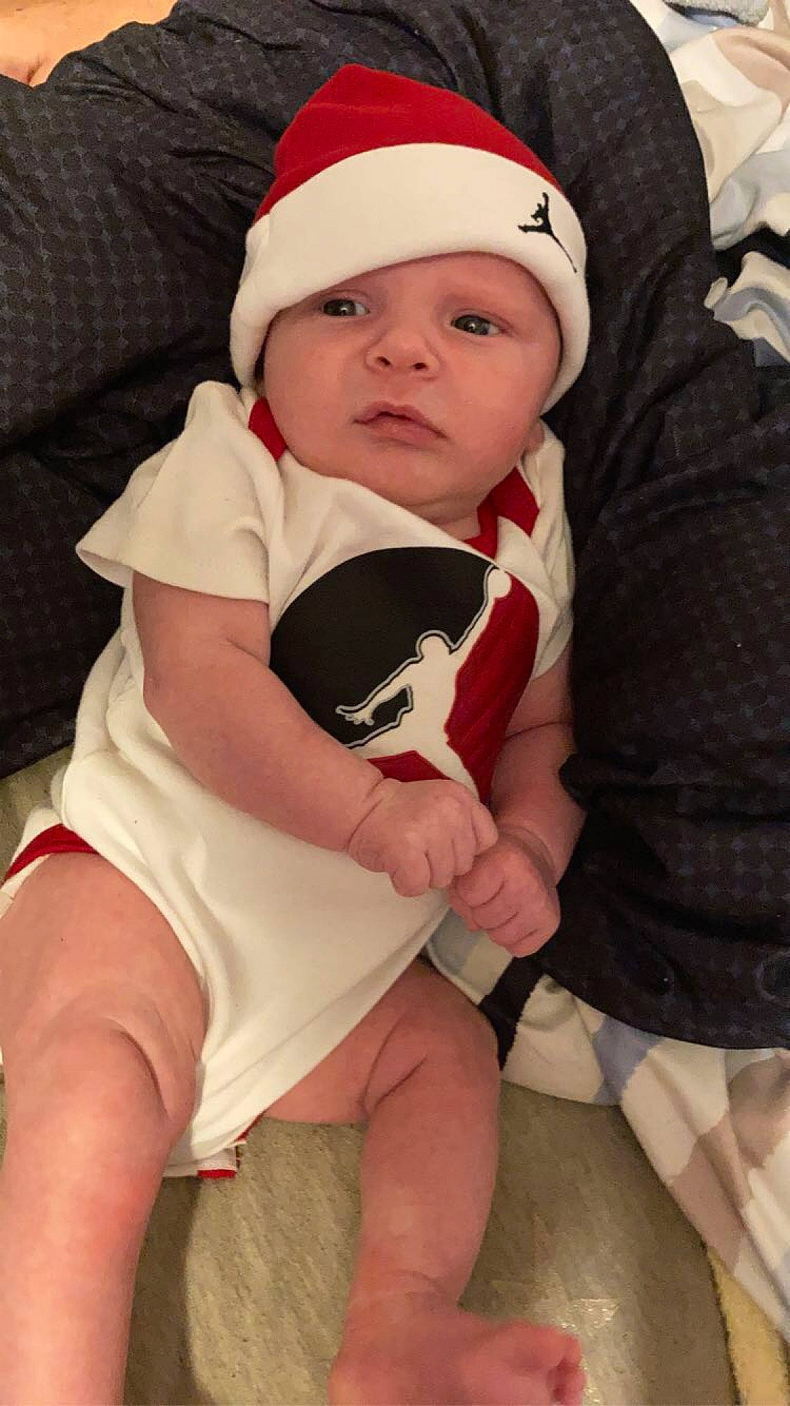 Tayson is registered to the contest to win money with this photo: baby, baby_toddler_clothing, cap, cheek, comfort, eye, face, finger, happy, head, headwear, human_body, knee, lap, mouth, people, person, pink, skin, sleeve