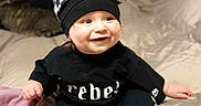 Ryder joined the competition — help win amazing prizes! animal, baby, bed, black_clothing, blanket, cat, checkered_cap, child, cozy, cute, furniture, happy, headwear, indoor, pacifier, person, portrait, sitting, smiling, sock