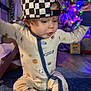 Ryder is registered to the contest to win money with this photo: baby, carpet, checkered_cap, child, christmas_tree, colorful, cute, festive, floor, footwear, hat, holiday_lights, indoors, onesie, playful, portrait, sitting, smiling, toddler, young_child