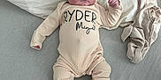 Ryder is registered to the contest to win money with this photo: baby, infant, onesie, hat, bed, pillow, blanket, clothing, newborn, person, cute, lying_down, soft_texture, indoor, relaxed, portrait, child, sleepwear, footwear, cozy