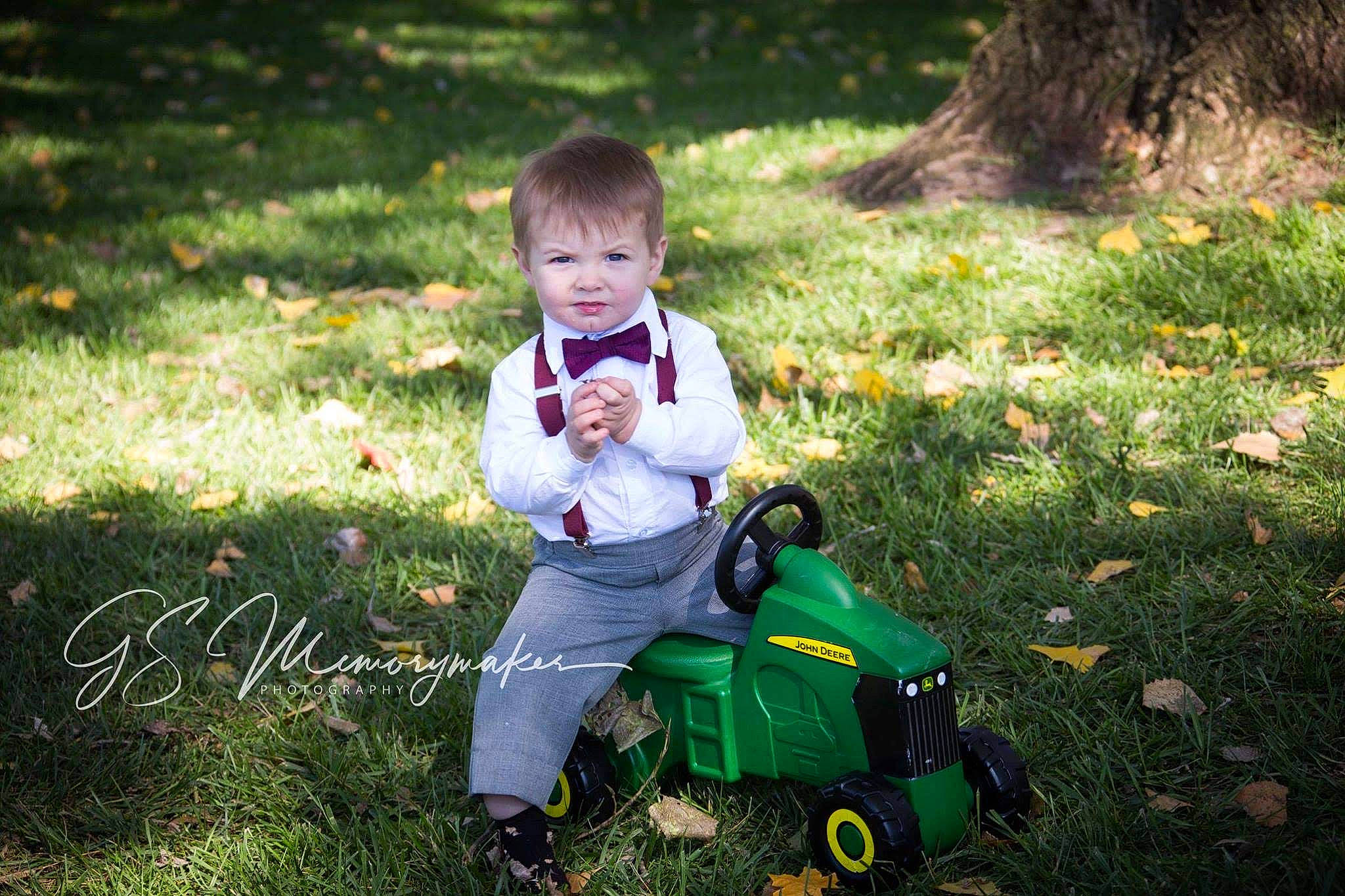 Gavin is registered to the contest to win money with this photo: child, grass, happy, lawn, leaf, person, plant, play, riding_toy, sitting, toddler, vehicle