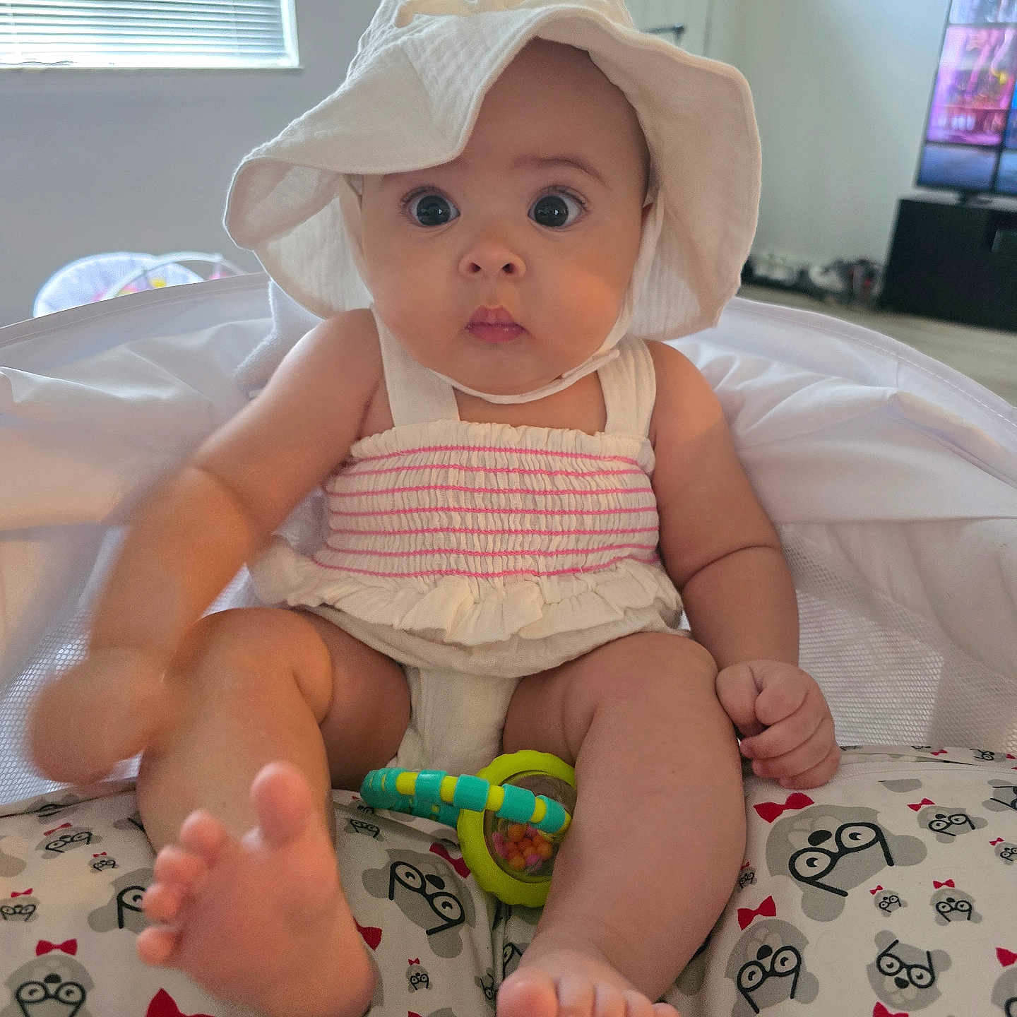 Geneva joined the competition — help win amazing prizes! baby, child, clothing, cushion, cute, foot, furniture, hand, hat, indoor, infant, monkey_pattern, patterned_cushion, rattle, room, sitting, toy, white_hat, wide_eyes, window