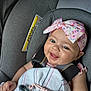 Geneva joined the competition — help win amazing prizes! baby, child, car_seat, headband, pink, smile, pacifier, blanket, infant, happy, cute, clothing, seatbelt, indoors, person, closeup, accessory, playful, adorable, safety