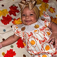 Kinlee joined the competition — help win amazing prizes! baby, smiling, headband, bow, dress, pumpkin, autumn, leaves, blanket, pattern, child, cute, happy, infant, face, portrait, clothing, lying_down, indoor, celebration