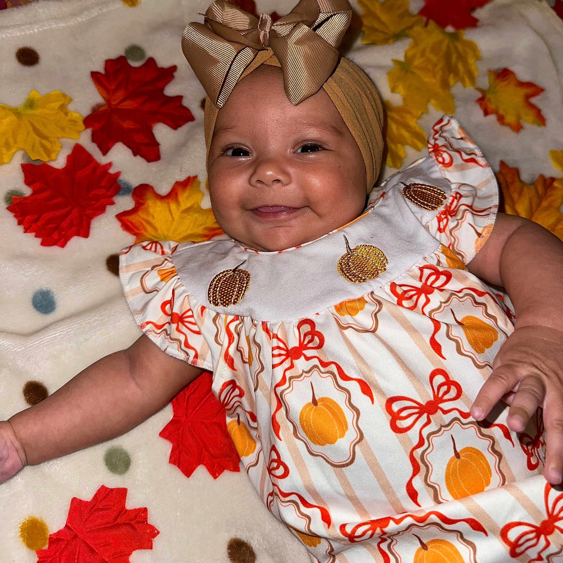 Kinlee joined the competition — help win amazing prizes! autumn, baby, blanket, bow, celebration, child, clothing, cute, dress, face, happy, headband, indoor, infant, leaves, lying_down, pattern, portrait, pumpkin, smiling
