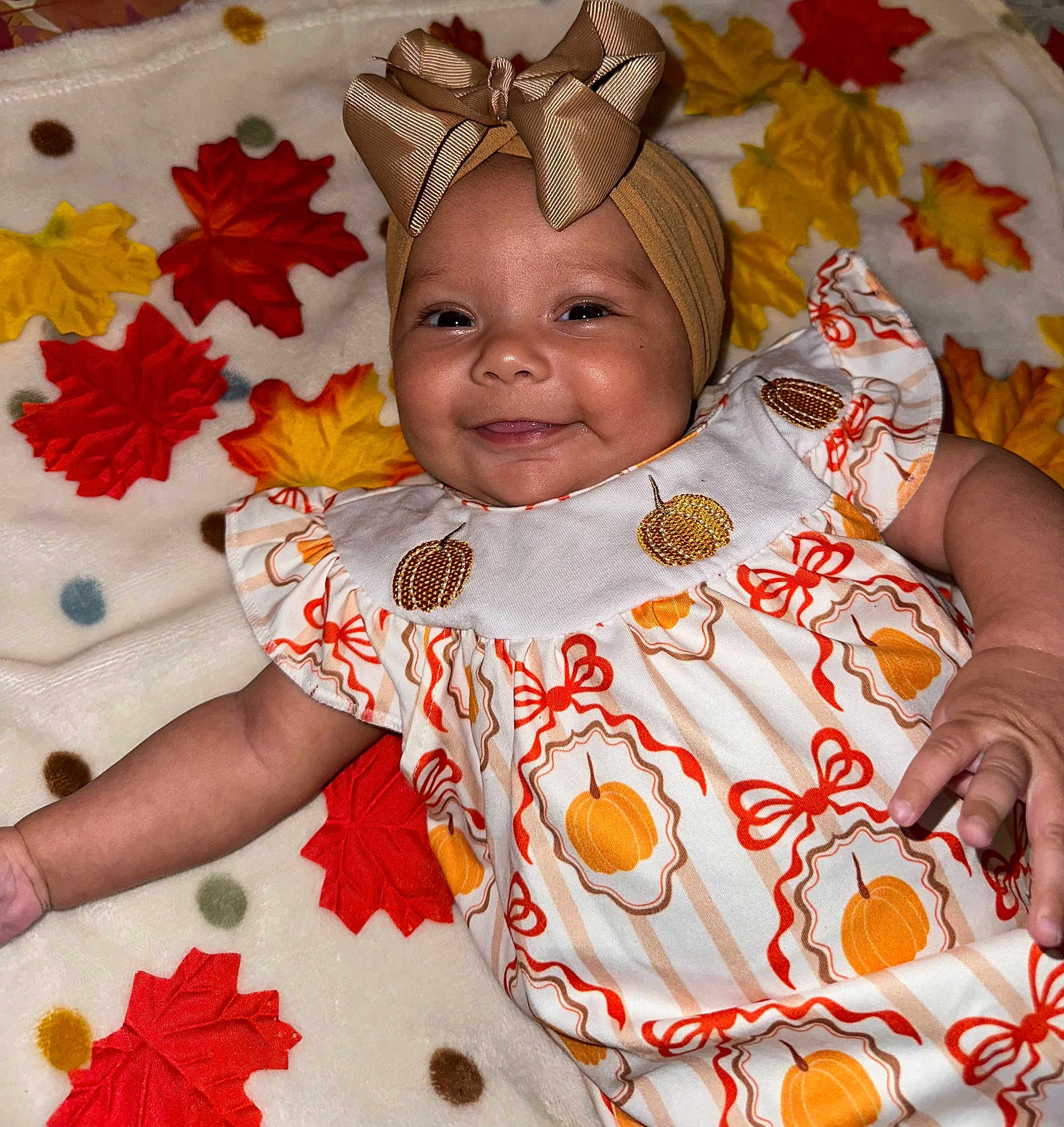 Kinlee joined the competition — help win amazing prizes! baby, smiling, headband, bow, dress, pumpkin, autumn, leaves, blanket, pattern, child, cute, happy, infant, face, portrait, clothing, lying_down, indoor, celebration