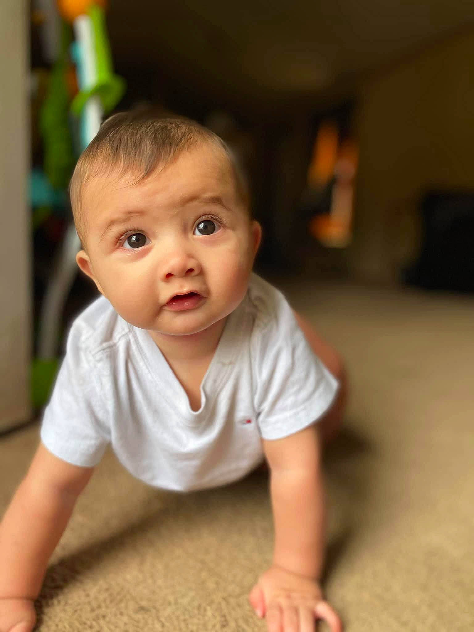 Jesus is registered to the contest to win money with this photo: baby, baby_crawling, baby_toddler_clothing, cheek, chin, eye, eyebrow, finger, floor, flooring, hair, happy, iris, leg, mouth, nose, person, skin, sleeve, toddler